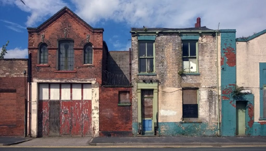 derelict houses and abandoned commercial property on a residential street with boarded up windows and decaying crumbling walls, apartment