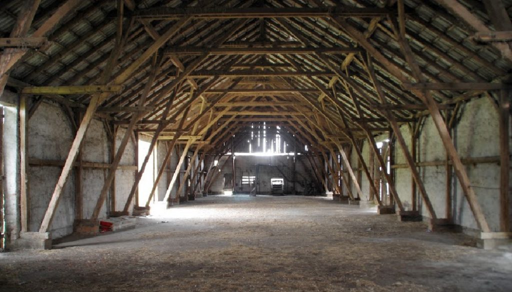 Empty rural barn with wooden supports and remains of hay on the floor; ancestors, family history, BillionGraves
