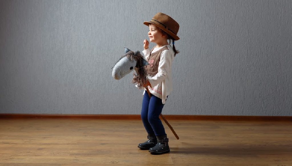 Cute little girl dressed like a cowboy playing with a homemade horse. Expressive facial expressions. BillionGraves