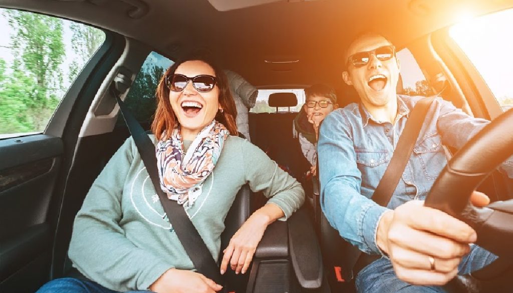 Cheerful young traditional family has a long auto journey and singing aloud the favorite song together. BillionGraves, genealogy, cemetery, Safety riding car concept wide angle view image.
