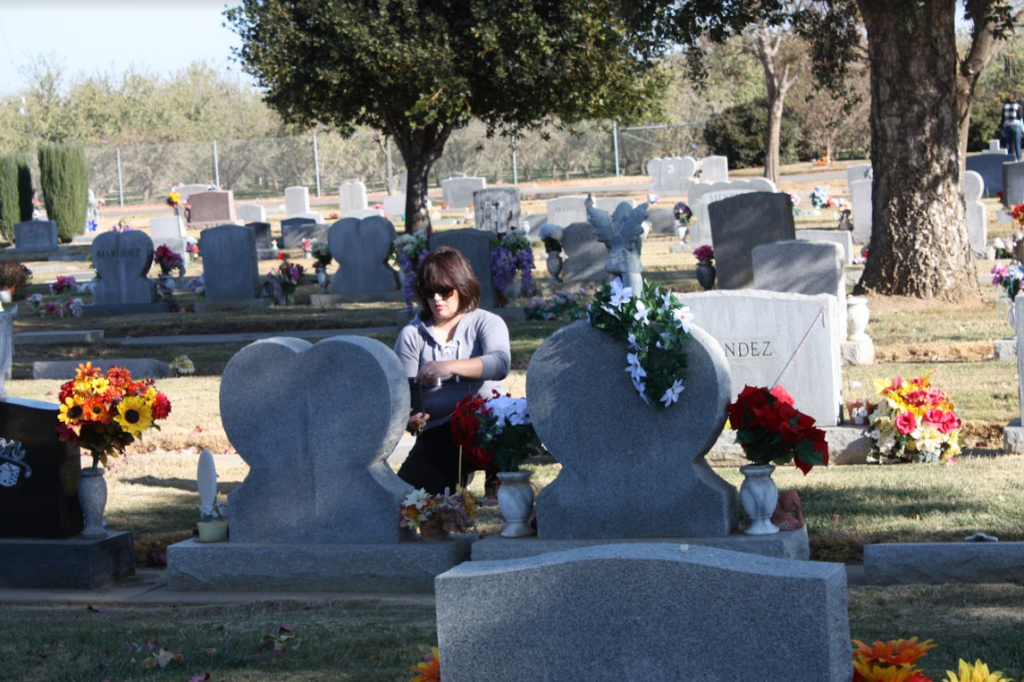 person taking photos in cemetery with BillionGraves app on smartphone of gravestones, floral arrangments, funeral, cemetery, grave, gravestones, ancestors, family history